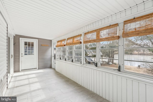 unfurnished sunroom featuring plenty of natural light and a water view