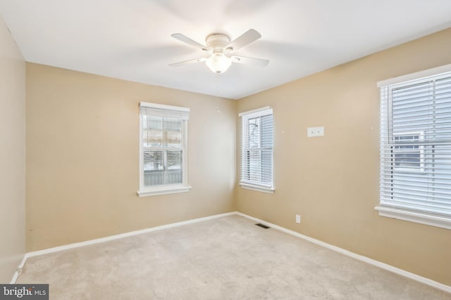 empty room with ceiling fan and light carpet