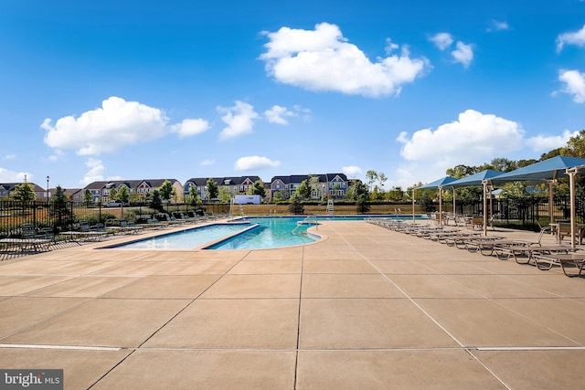 community pool with a patio area and fence