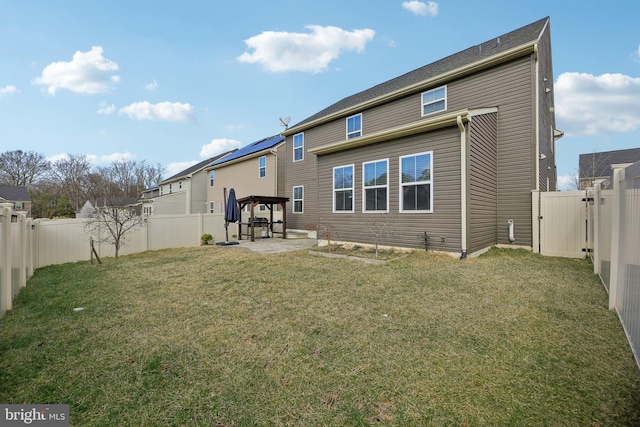 back of property featuring a yard, a fenced backyard, and a gate