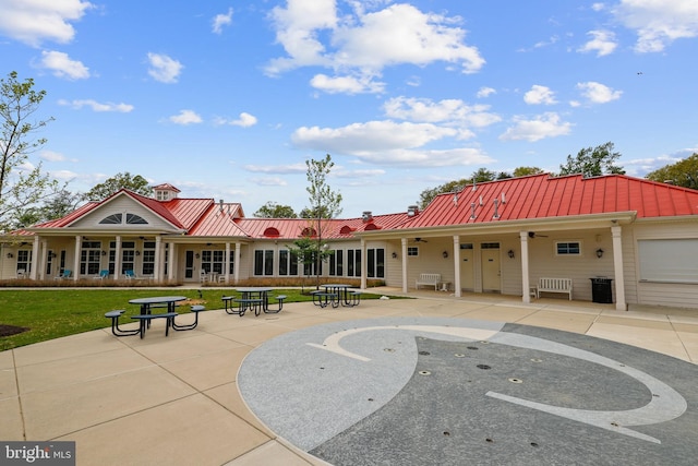 exterior space with a standing seam roof, a lawn, metal roof, and a patio