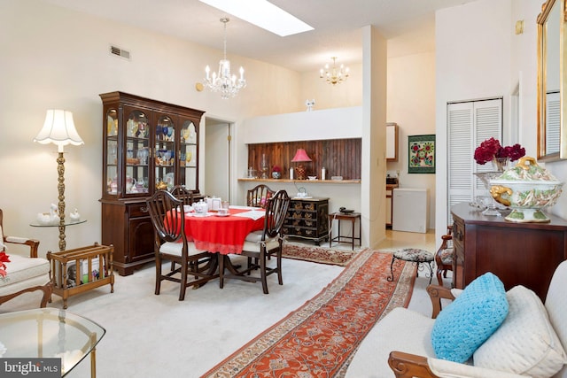 dining space with a chandelier, a high ceiling, a skylight, visible vents, and carpet