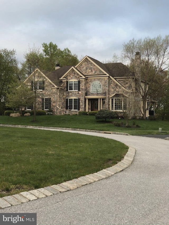 view of front facade with stone siding, a chimney, and a front yard