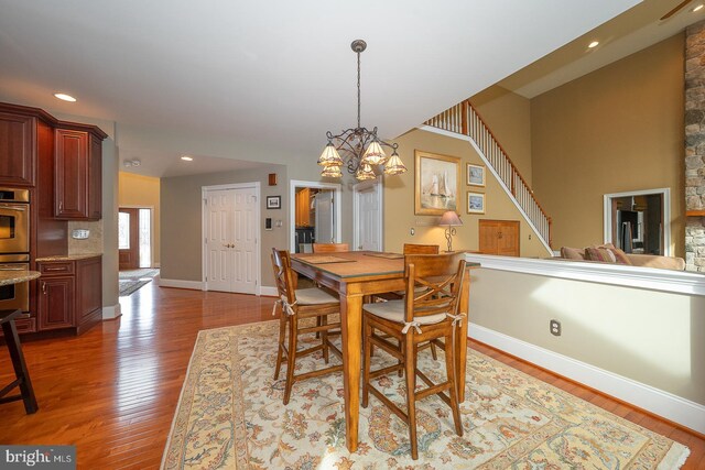 dining room with baseboards, stairway, wood finished floors, an inviting chandelier, and recessed lighting