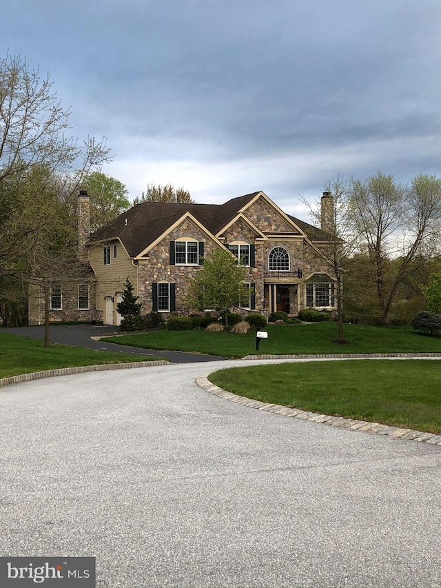 view of front of house with a chimney, a front lawn, and aphalt driveway