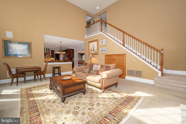 living area with baseboards, visible vents, light colored carpet, a towering ceiling, and stairway