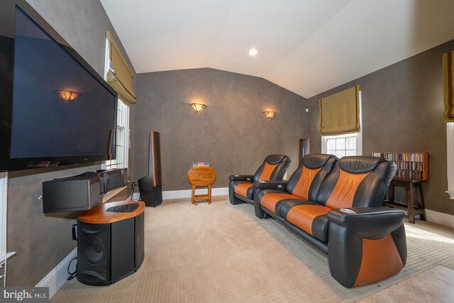 cinema room featuring vaulted ceiling, baseboards, and light colored carpet