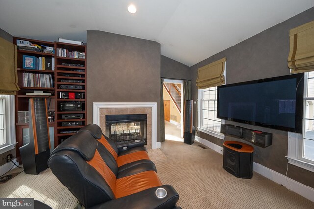 living room with light colored carpet, baseboards, vaulted ceiling, and a tile fireplace