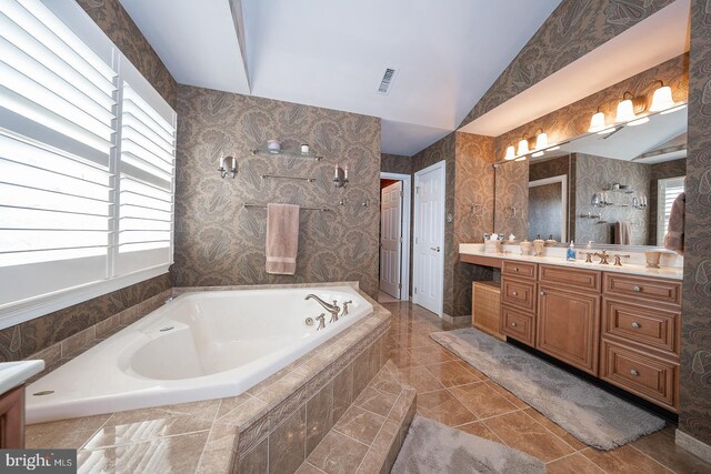 bathroom featuring visible vents, a garden tub, tile patterned flooring, vaulted ceiling, and vanity