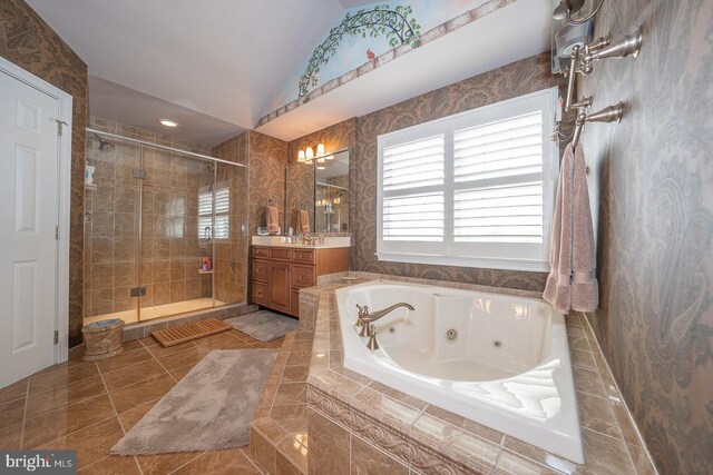 full bathroom featuring vaulted ceiling, vanity, a shower stall, a jetted tub, and tile patterned floors