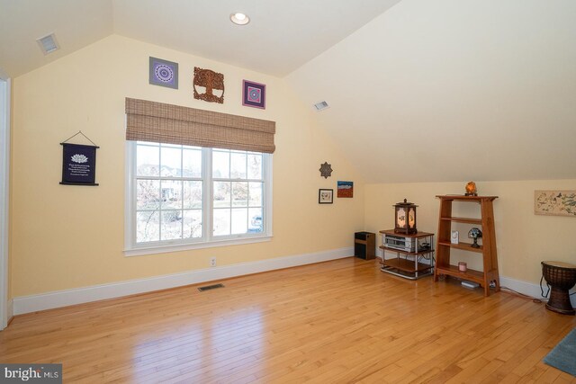 additional living space featuring light wood-style flooring, visible vents, and vaulted ceiling