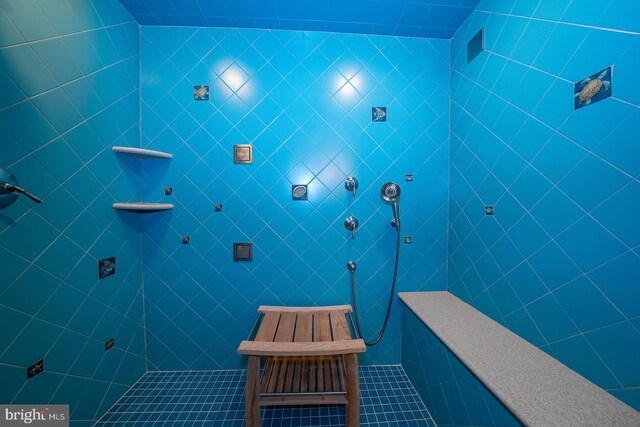 bathroom with a tile shower and tile walls