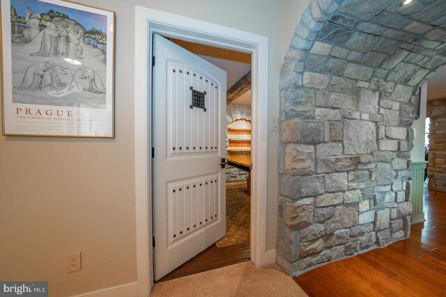 corridor featuring arched walkways and wood finished floors