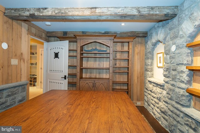 unfurnished dining area with wood walls, radiator heating unit, and beamed ceiling