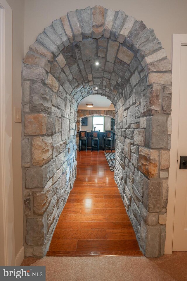 corridor with arched walkways and wood finished floors