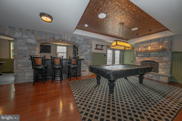 recreation room featuring dark wood-type flooring, a community bar, wainscoting, a tray ceiling, and an ornate ceiling