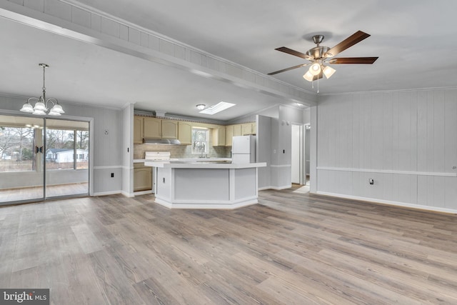 kitchen featuring pendant lighting, white fridge, ornamental molding, a kitchen island, and light wood-type flooring