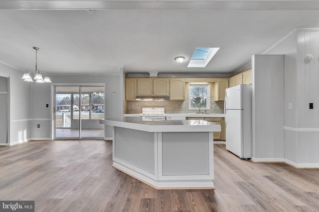 kitchen featuring sink, range, hanging light fixtures, white fridge, and light wood-type flooring