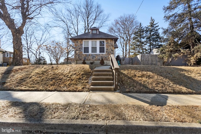 view of front of home featuring stone siding and fence