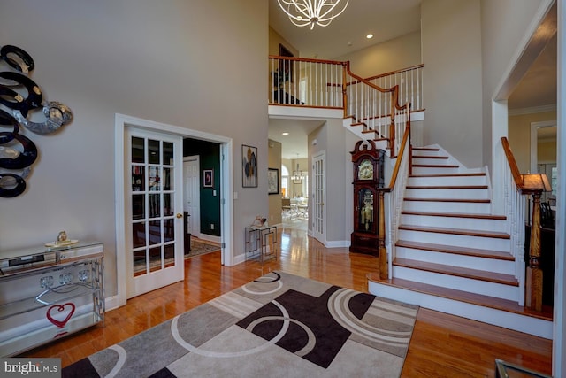 entrance foyer with light wood-style floors, stairway, a notable chandelier, and french doors