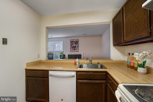 kitchen featuring white appliances, dark brown cabinets, light countertops, and a sink