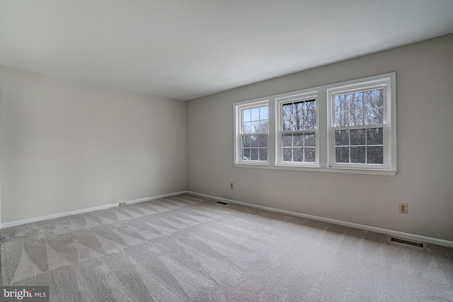 empty room featuring light carpet, baseboards, and visible vents