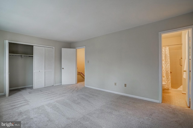 unfurnished bedroom featuring baseboards, a closet, ensuite bath, and light colored carpet