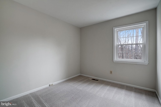 spare room with carpet flooring, visible vents, and baseboards