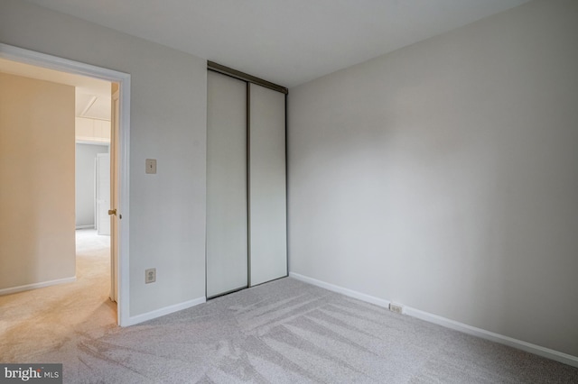 unfurnished bedroom featuring baseboards, a closet, and light colored carpet