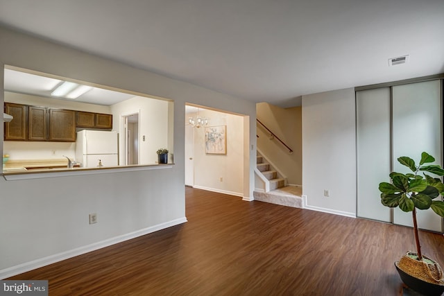 unfurnished living room with dark wood-style flooring, stairway, visible vents, and baseboards