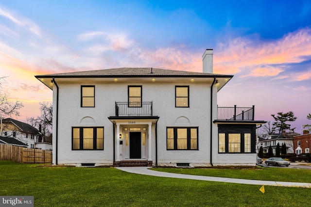 view of front of house featuring a balcony and a lawn