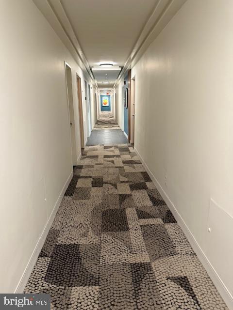 hall with dark colored carpet