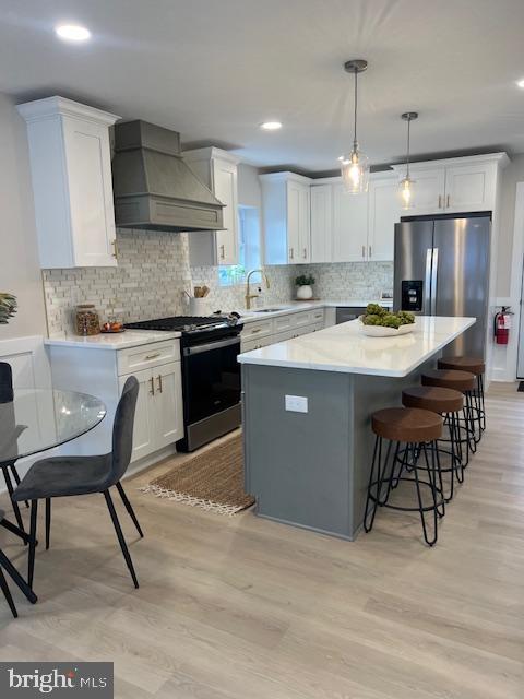 kitchen with pendant lighting, white cabinetry, a center island, gas range oven, and custom exhaust hood