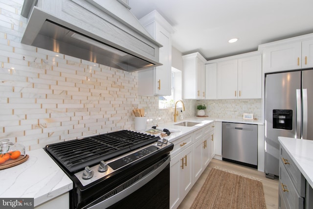 kitchen featuring sink, white cabinetry, stainless steel appliances, light stone countertops, and custom range hood