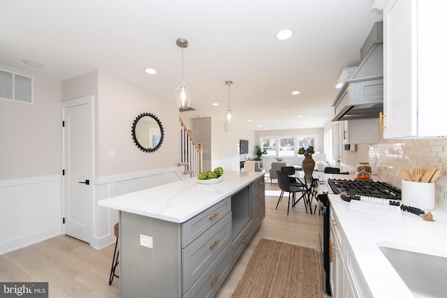 kitchen featuring gray cabinets, a breakfast bar, pendant lighting, white cabinets, and a center island