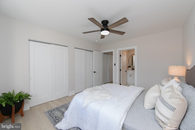 bedroom with connected bathroom, two closets, ceiling fan, and light hardwood / wood-style flooring