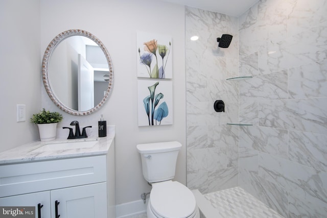 bathroom featuring a tile shower, vanity, and toilet