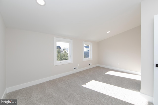 carpeted spare room with vaulted ceiling