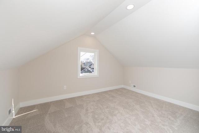 bonus room with vaulted ceiling and light carpet