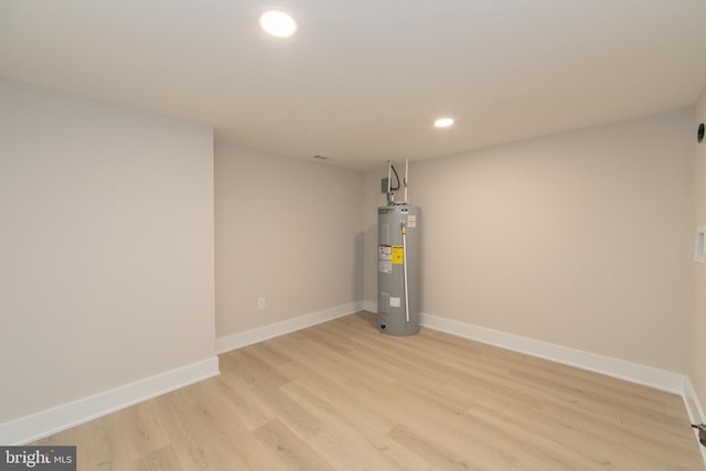 basement featuring light hardwood / wood-style flooring and water heater