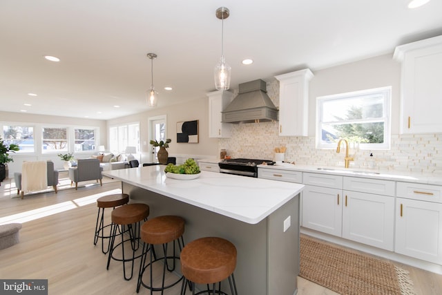 kitchen featuring pendant lighting, white cabinets, custom exhaust hood, and stainless steel range oven