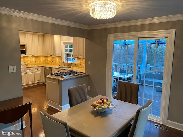 dining room featuring ornamental molding, sink, dark wood-type flooring, and a notable chandelier