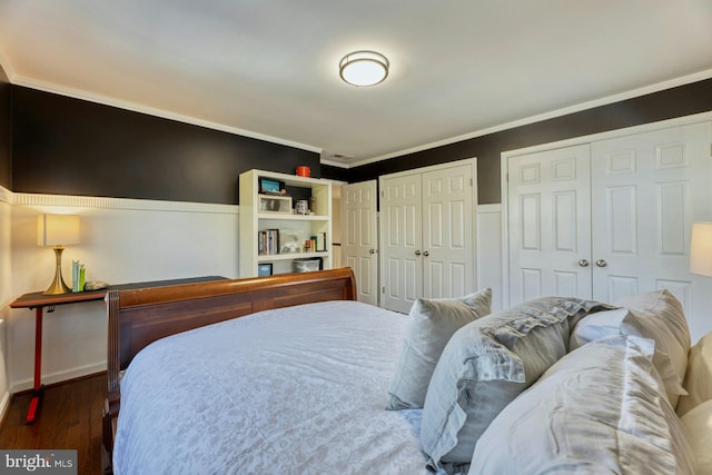 bedroom featuring multiple closets, crown molding, and dark hardwood / wood-style floors