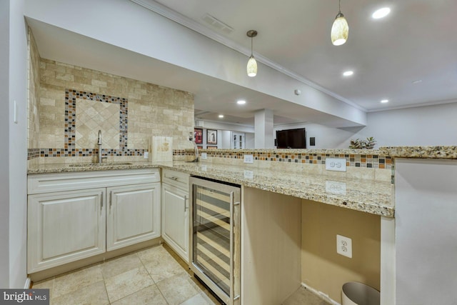 kitchen featuring pendant lighting, sink, wine cooler, backsplash, and light stone countertops