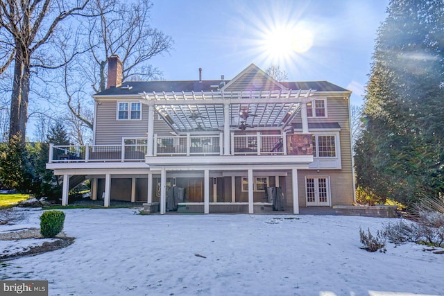 snow covered property with a wooden deck, a pergola, and french doors