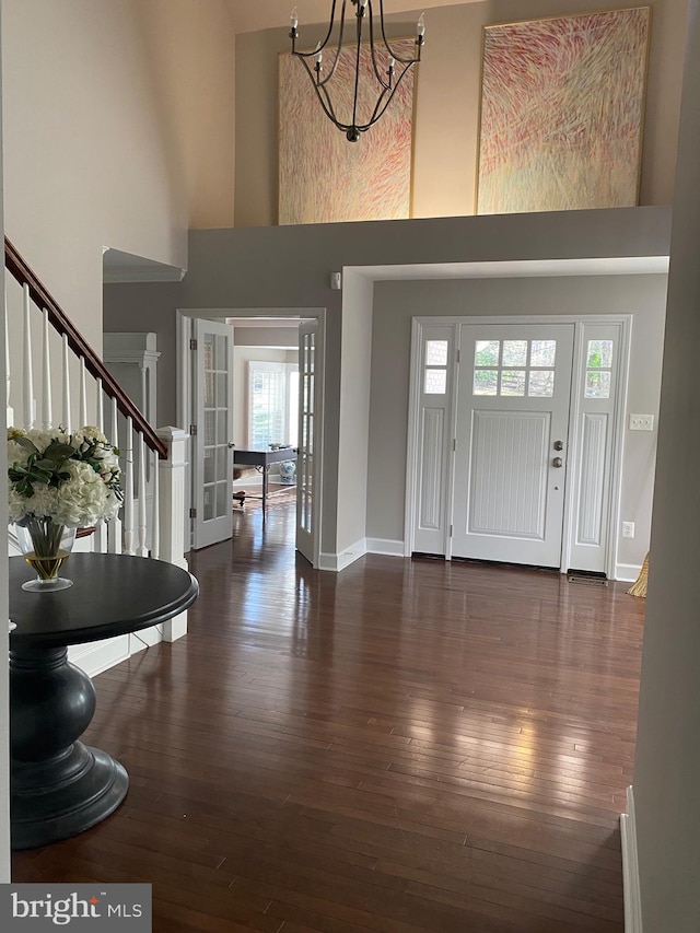 foyer featuring a towering ceiling, dark hardwood / wood-style floors, and a notable chandelier