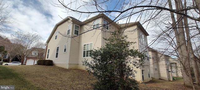 view of side of property with a garage and a lawn