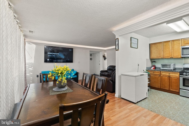 dining room with a textured ceiling and light wood-type flooring