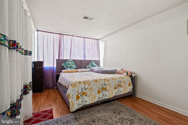 bedroom featuring crown molding, a textured ceiling, and light wood-type flooring