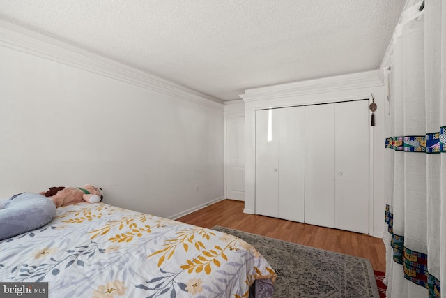 bedroom featuring crown molding, a closet, hardwood / wood-style floors, and a textured ceiling